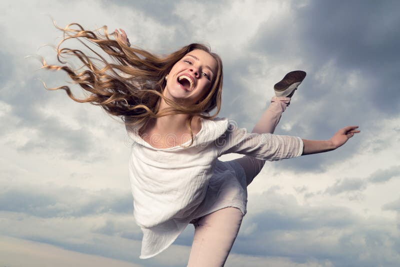 Beautiful happy smiling woman with hair flying in the sky background