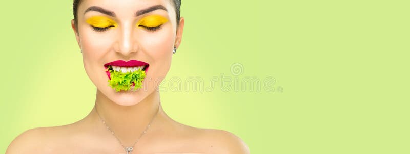 Beautiful healthy girl eating raw vegan food and smiling. Lips. Beauty young fashion woman eats green fresh lettuce salad leaf