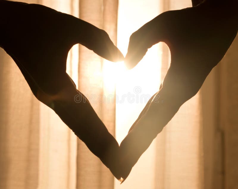 Heart made from hands, with light shining through - warm sun light shining through sheer curtains. Heart made from hands, with light shining through - warm sun light shining through sheer curtains