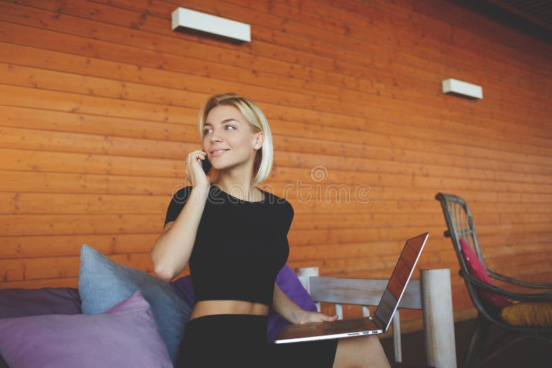Young woman is smiling for friends during talk via smart phone, while is sitting in modern co-working space. stock images Young woman is smiling for friends during talk via smart phone, while is sitting in modern co-working space. stock images