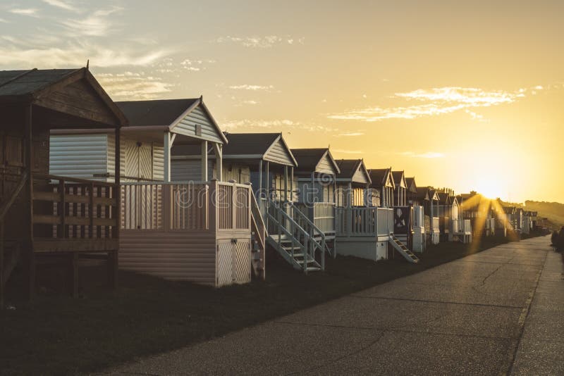 Beautiful Horizontal Shot Of White Cabins With Grey Rooftops During Sunset Under The Colorful Sky