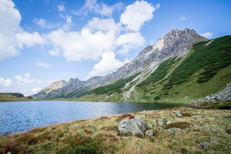 Beautiful and idyllic mountain landscape scenery: Mountain range, lake with clear water and blue cloudy sky