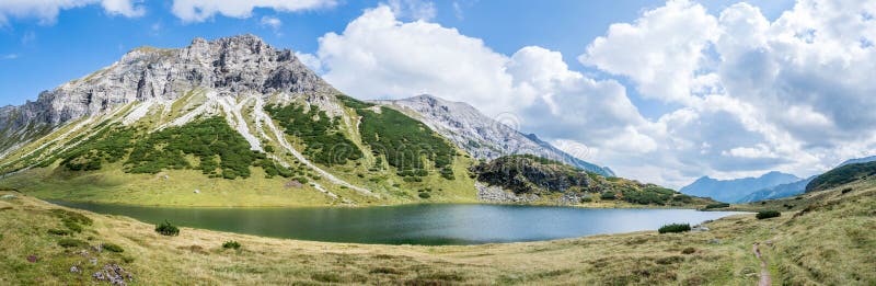Beautiful and idyllic mountain landscape scenery: Mountain range, lake with clear water and blue cloudy sky; Panorama. Mountain landscape: Rocky mountain range stock photo Beautiful and idyllic mountain landscape scenery: Mountain range, lake with clear water and blue cloudy sky; Panorama. Mountain landscape: Rocky mountain range stock photo