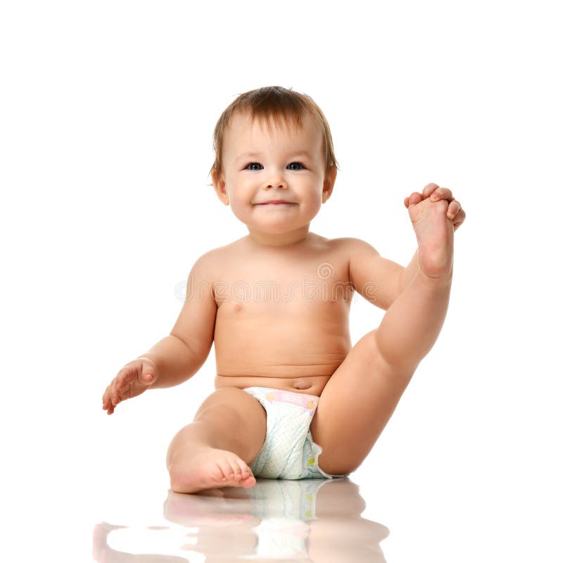 Beautiful infant baby girl toddler sitting in diaper and hold one leg