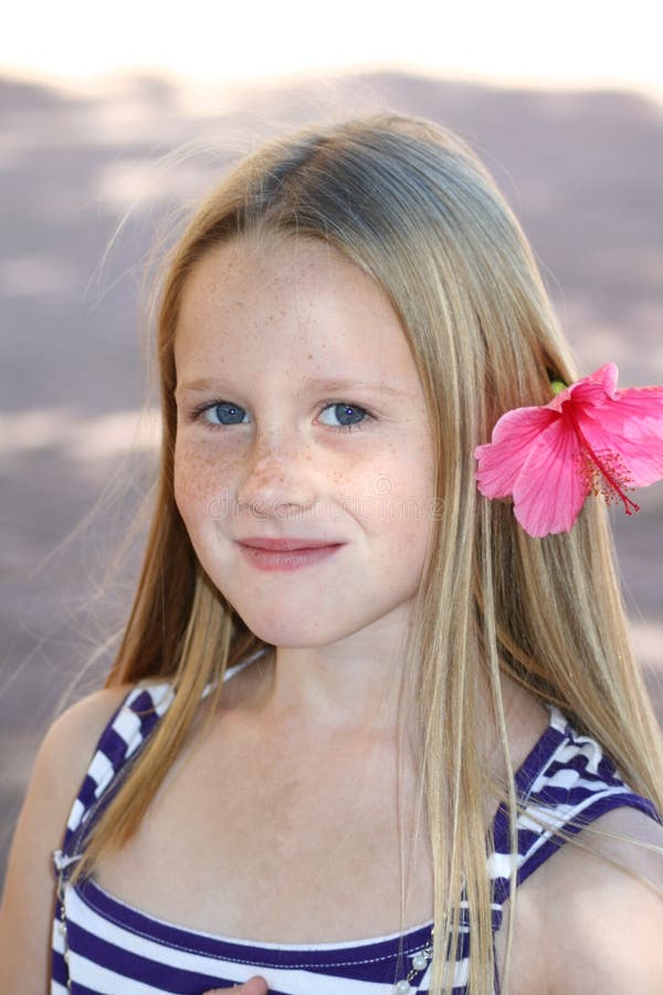 A beautiful white caucasian girl child playing in the garden with a pink flower in her hair. A beautiful white caucasian girl child playing in the garden with a pink flower in her hair.