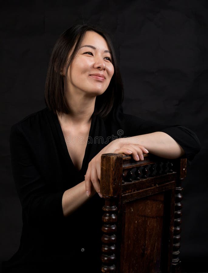Beautiful Korean Woman Dressed In Black Dress Sitting On Sofa Stock