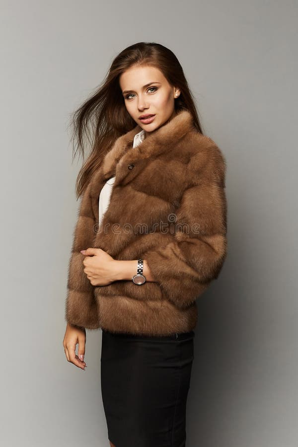 Beautiful lady with elegant hairstyle in luxury fur coat,  in the background. Fashion artificial fur. Beautiful