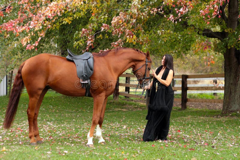 Beautiful lady standing with her horse in Autumn