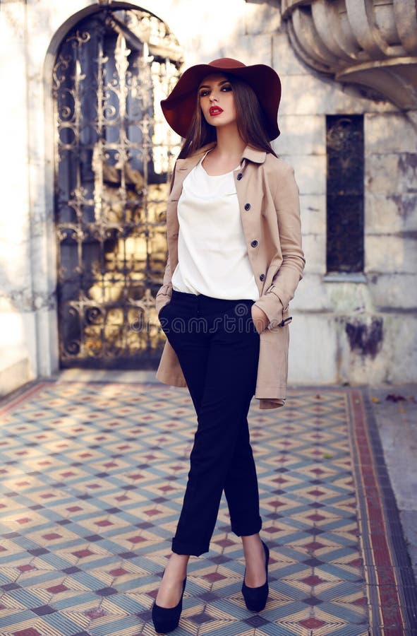 Mode im freien Foto der schönen eleganten Frau mit dunklem glattem Haar, tragen elegante Mantel und Hut, die sich im Palast.