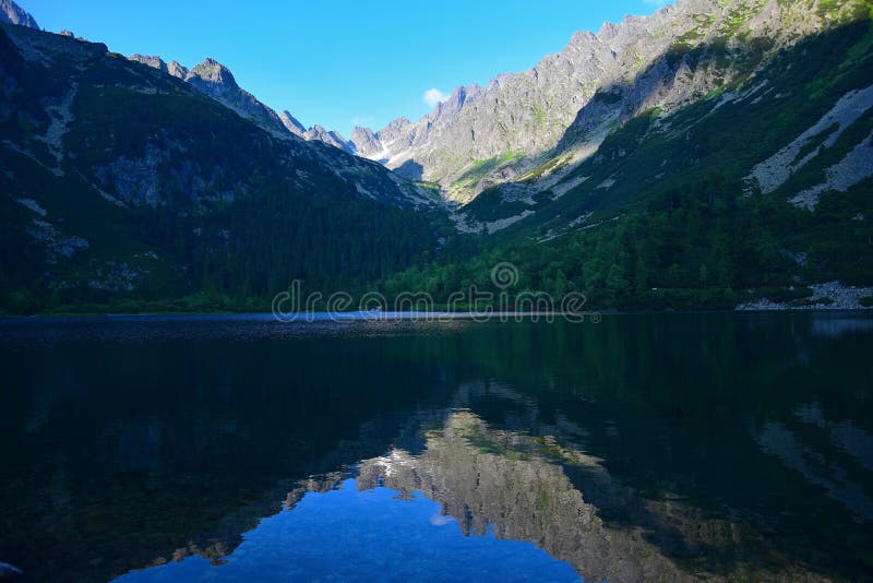 Nádherné Popradské pleso vo Vysokých Tatrách vo večernom slnku s odrazom hôr. Slovensko