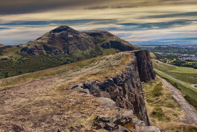 Beautiful landscape of Arthur`s Seat mountain in Scotland with path on the cliff and Edinburgh city in the background