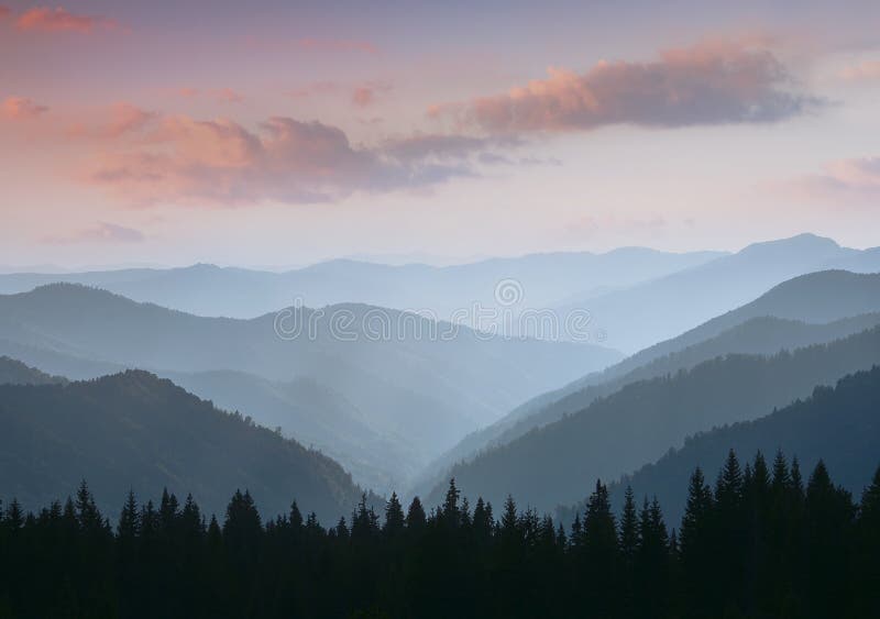 Beautiful landscape of summer mountains at sunrise. Misty slopes of the mountains in the distance.