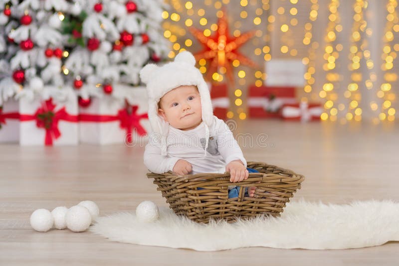 Beautiful little baby boy celebrates Christmas. New Year`s holidays. Baby in a Christmas costume casual clothes with gifts on fur