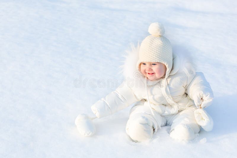 Beautiful little baby girl sitting in white snow