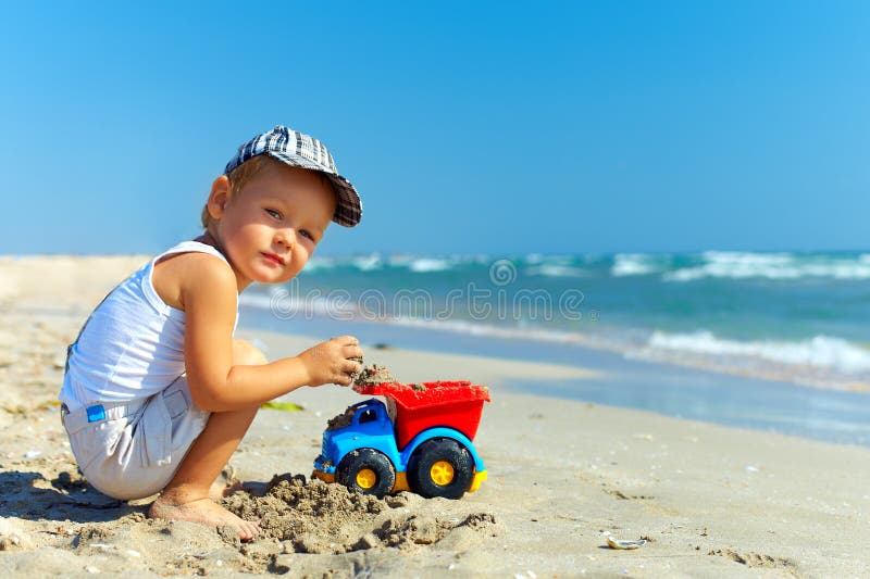 Little boy lying on top of beach ball at the beach 