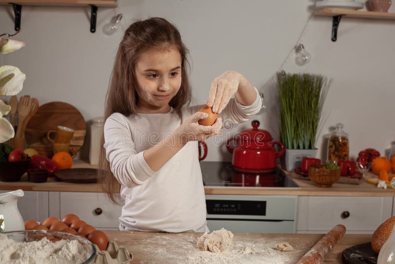 Beautiful little girl dressed in a white blouse is making a dough for baking a bread at a kitchen. stock image Beautiful little girl dressed in a white blouse is making a dough for baking a bread at a kitchen. stock image