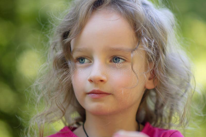 Beautiful little curly blonde girl, has serious expression, look into the distance, big blue eyes, long eyelashes