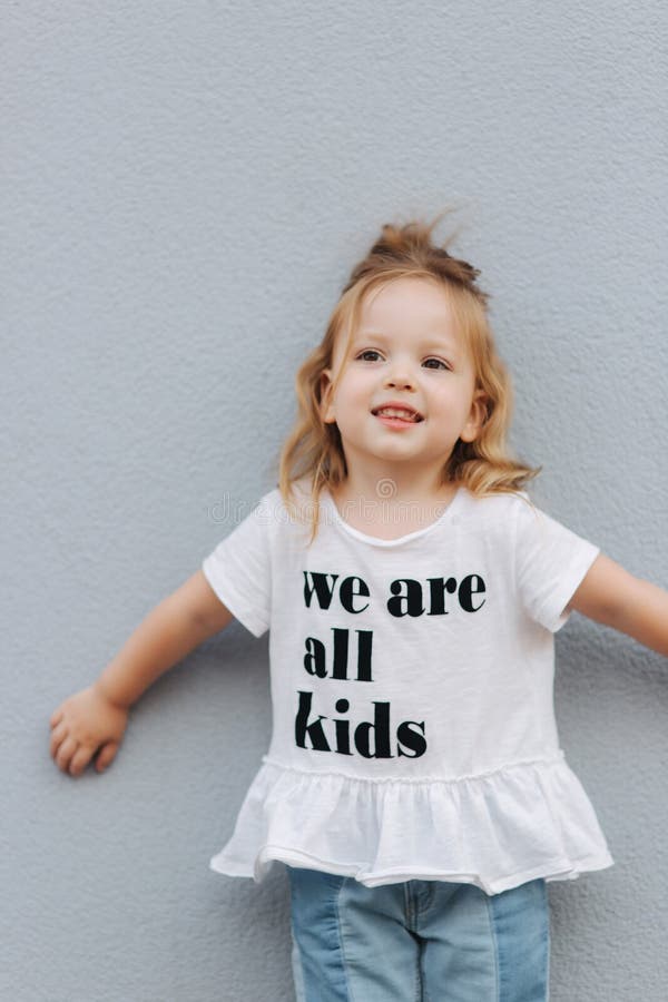 Beautiful Little Girl Dressed in White Shirt and Jeans Stand in Front ...