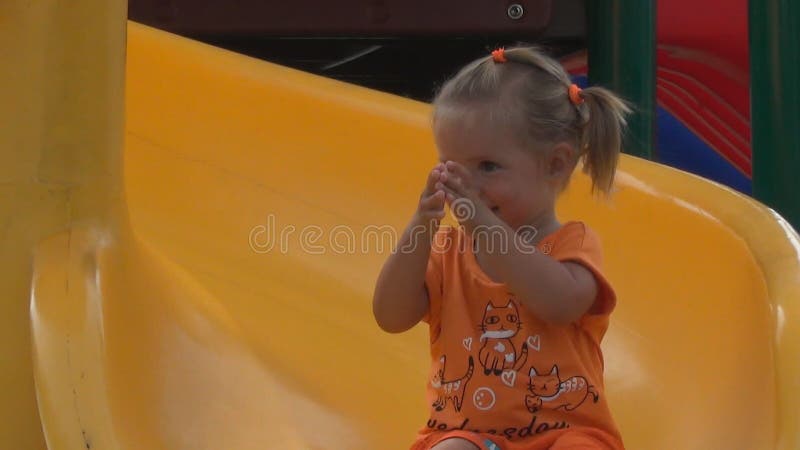 Beautiful little girl goes for a drive on a children s hill. she claps her hands