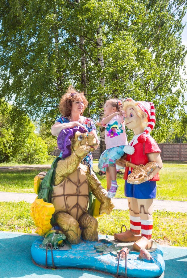Beautiful little girl with grandmother on the playground with Pinocchio and a turtle royalty free stock images Beautiful little girl with grandmother on the playground with Pinocchio and a turtle royalty free stock images
