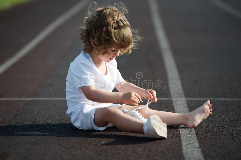 Beautiful little girl learning to tie shoelaces