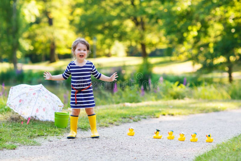 Beautiful little girl of 2 playing with yellow rubber ducks in s
