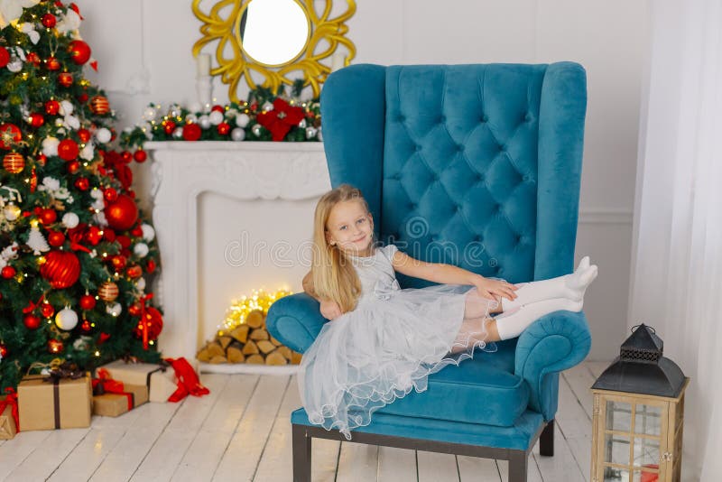 Beautiful little girl sitting on a chair by the tree.