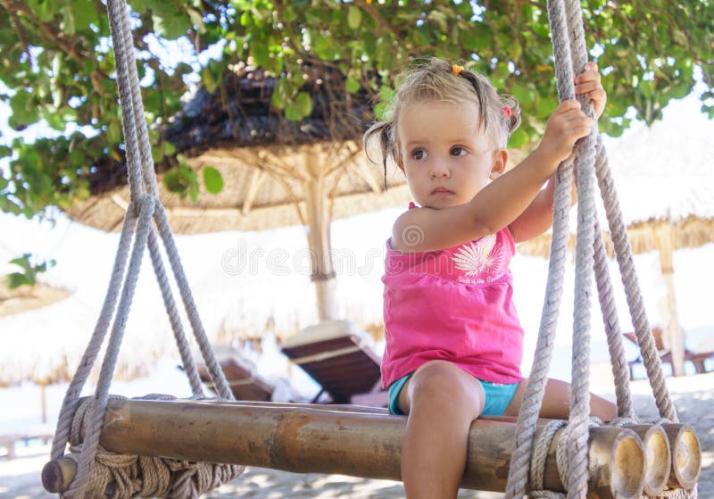 Beautiful little girl sitting rope swings on the beach. royalty free stock image Beautiful little girl sitting rope swings on the beach. royalty free stock image