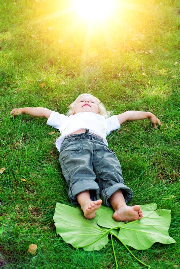Beautiful little toddler girl happy lying on grass. Beautiful little toddler girl happy lying on green grass royalty free stock photography