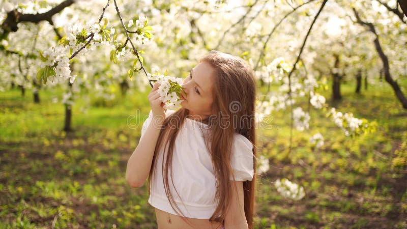 Beautiful long-haired teenage girl with a branch of a flowering tree in hands