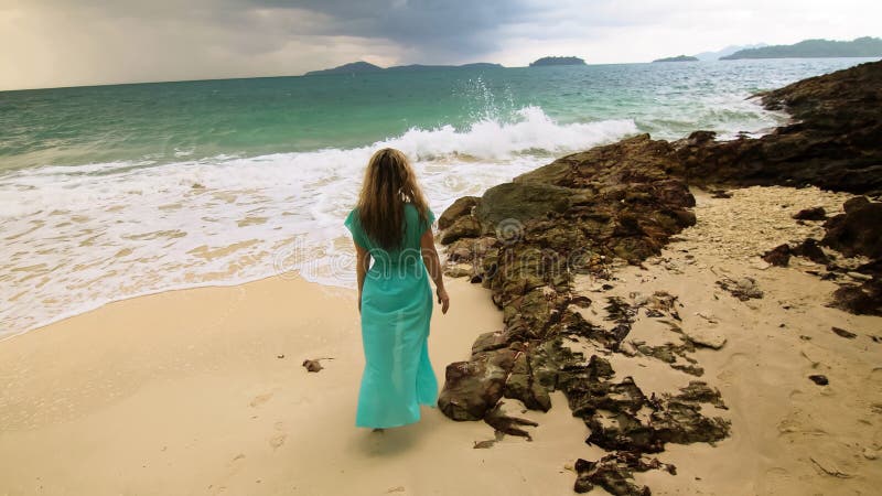 Woman Walks To The Stormy Cloudy Ocean On Sand Beach Girl In Blue