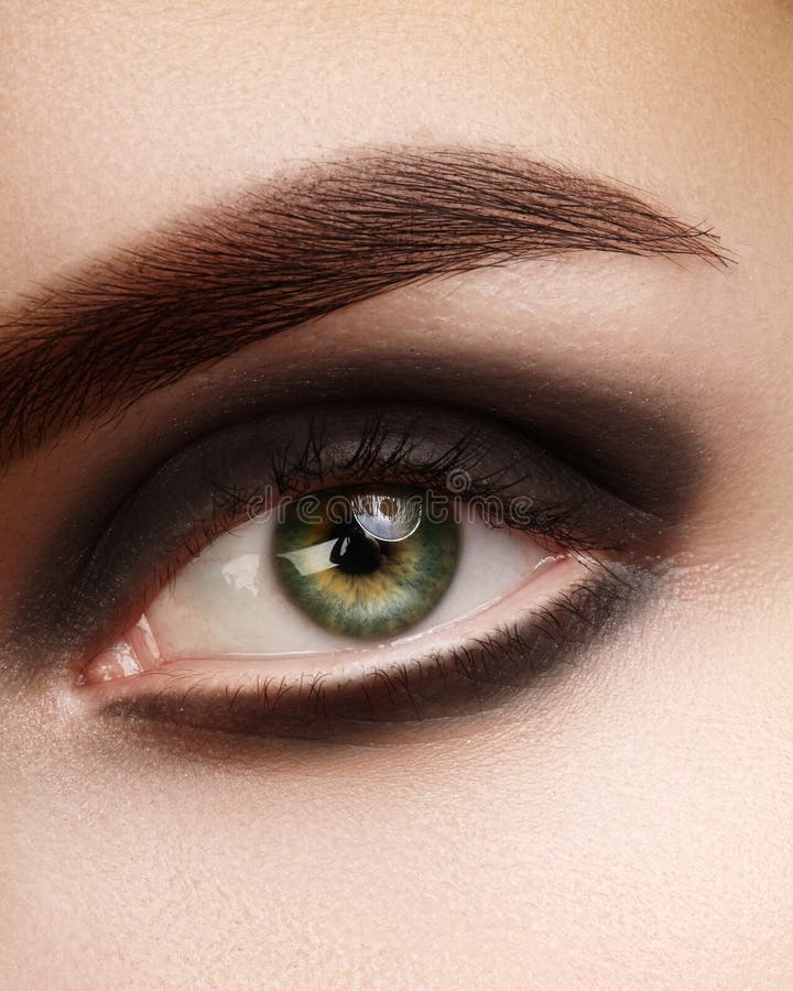 Beautiful macro photo of woman eye with black smoky makeup. Perfect shape eyebrows. Cosmetics and make-up stock images Beautiful macro photo of woman eye with black smoky makeup. Perfect shape eyebrows. Cosmetics and make-up stock images