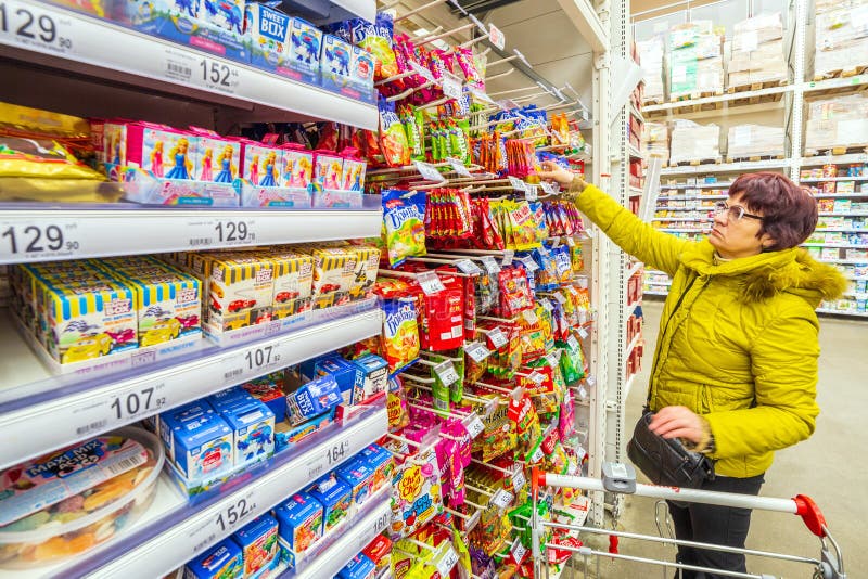 A beautiful mature woman is choosing goodies for her grandchildren in a supermarket. royalty free stock image A beautiful mature woman is choosing goodies for her grandchildren in a supermarket. royalty free stock image