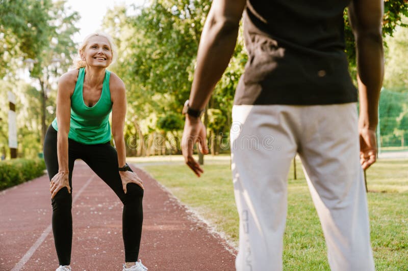 Beautiful Mature Woman Doing Workout With Fitness Trainer Outdoors In