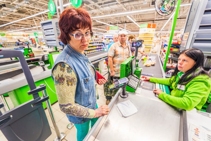 A beautiful mature woman is paying for the purchase of products in the supermarket by credit card. Russian text: tobacco