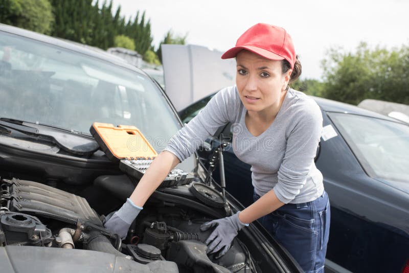 Beautiful mechanic woman working on car.