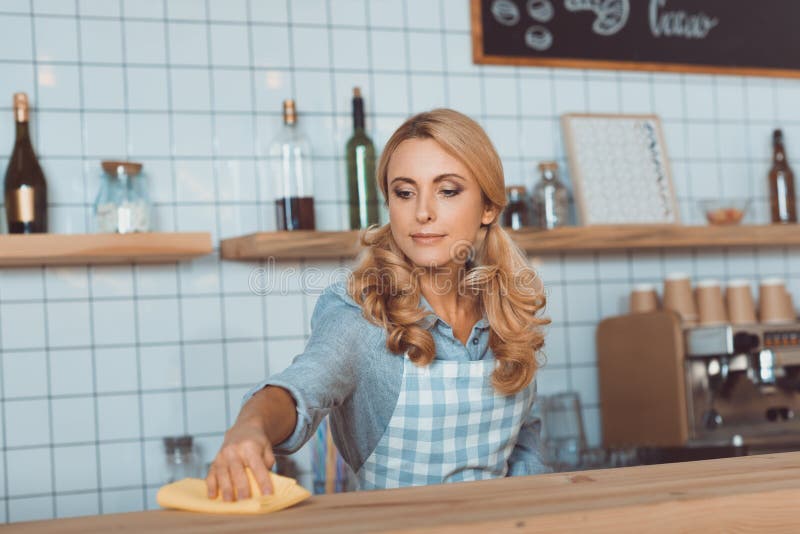 Beautiful Middle Aged Waitress In Apron Cleaning Bar Counter Stock