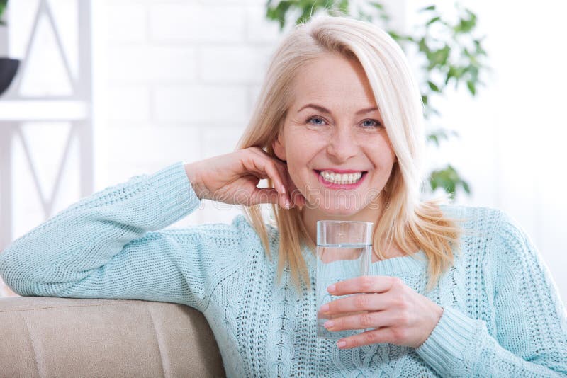 Beautiful middle aged woman drinking water in the morning