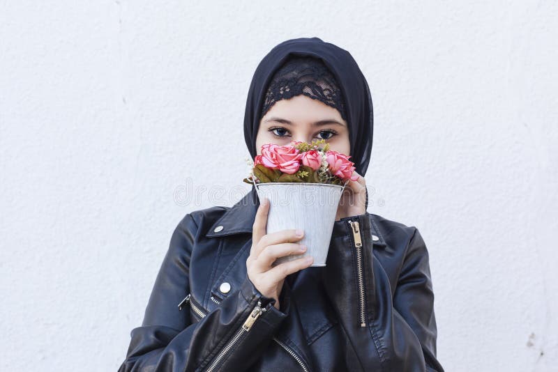 Beautiful middle-eastern girl holding decorative basket full of flowers. Cute Arabian Muslim woman received unique flower bouquet