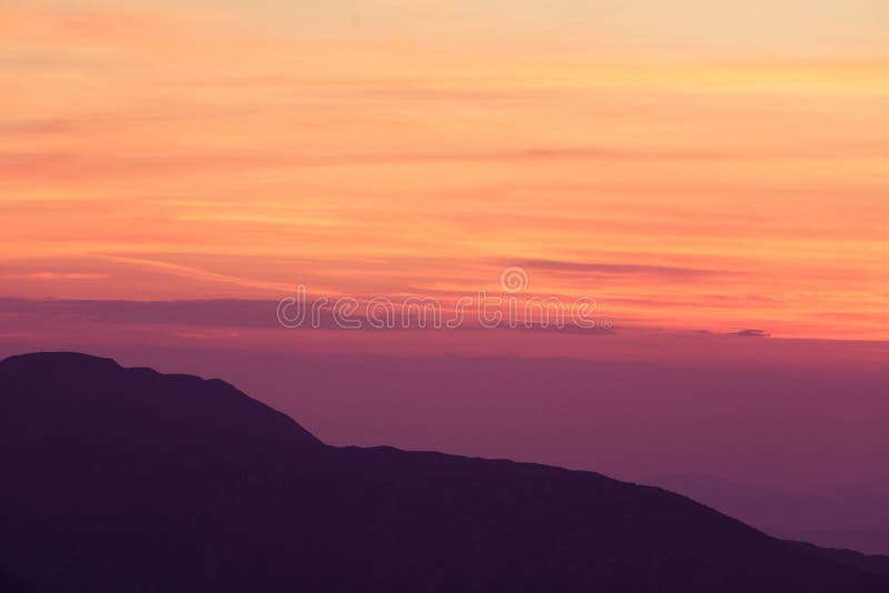 A beautiful, minimalist scenery of mountain sunset in purple tones. Abstract, colorful mountain landscape.