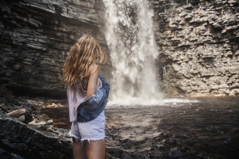 Premium Photo | A beautiful young girl is posing near a waterfall vacation  concept