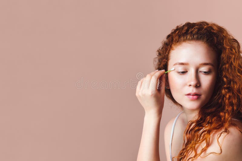 A Beautiful Model with Red Curly Hair Uses a Cotton Swab To Remove Makeup  from Her Eyes. Shot in a Studio on a Pink Background Stock Image - Image of  cotton, attractive: