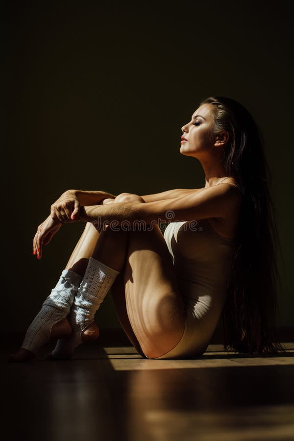 Beautiful modern ballet dancer with perfect body sits on the floor in the studio hall. royalty free stock photos Beautiful modern ballet dancer with perfect body sits on the floor in the studio hall. royalty free stock photos