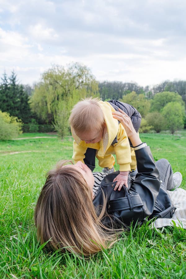 Un moment frumos mama ridicarea fiul într-un parc de primăvară. stock image
