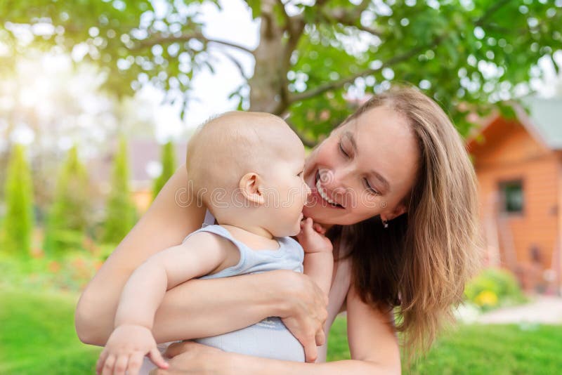 Beautiful mother with cute little baby boy having fun outdoors. Portrait of mom with fun child smiling in green summer garden.