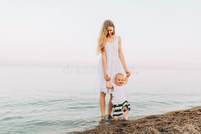 Beautiful mother playing on the beach with her little cute son