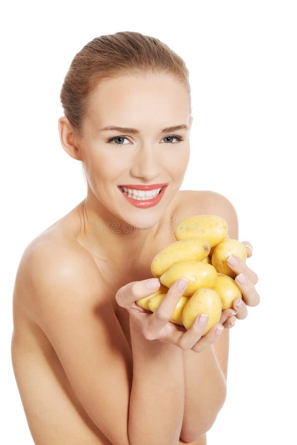 Beautiful naked woman holding raw potatoes in hands. 
