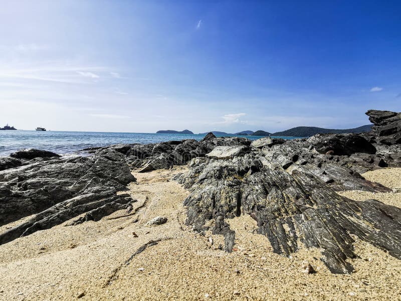Beautiful nature background - Black stones are lined up by the blue sea. On a clear day at Panwa Cape, Phuket, Thailand. Another