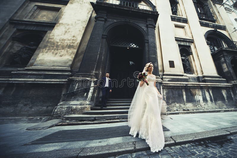 Beautiful newlywed couple posing near old church, elegant bride stock photography Beautiful newlywed couple posing near old church, elegant bride stock photography