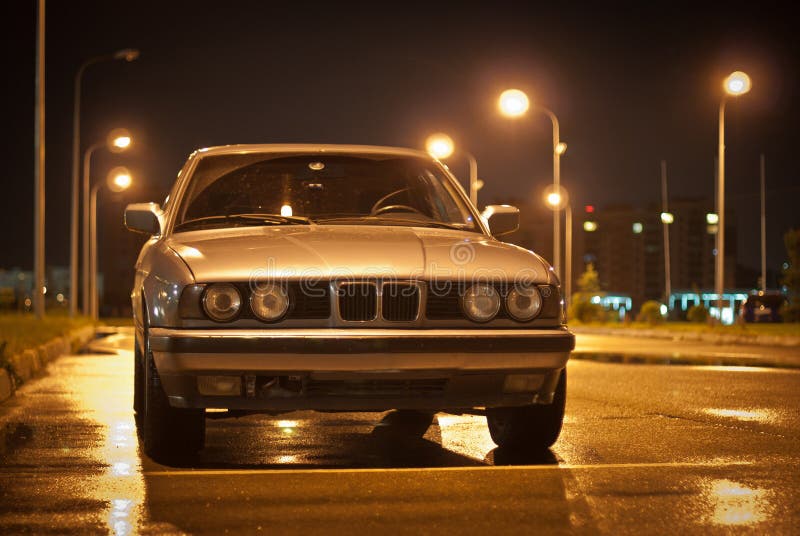 Beautiful old car. Golg old BMW of 5 series, front view. Street night from lamps. Night scene, car in the light of lamps royalty free stock photo